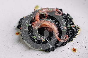 Black risotto with cuttlefish ink and octopus tentacles on irregular shape plate