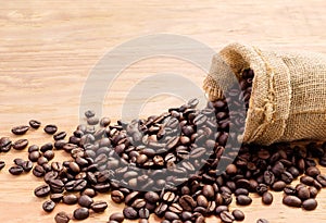 Black roasted coffee beans in a small burlap sack on wooden floor, Vintage style