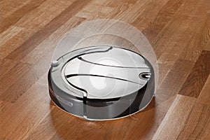 Black robot vacuum cleaner on parquet floor cleaning dust in the room. smart robotic automate wireless cleaning technology