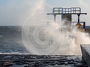 Black Rock diving rock at storm and high tide covered by a giant splash of water. Salthill, Galway city, Ireland