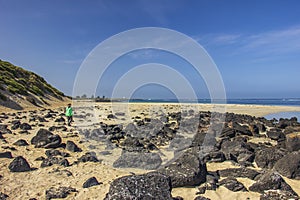 Black rocks scattered on the sandy beach of Griffiths Island of Port Fairy in Victoria, Australia.