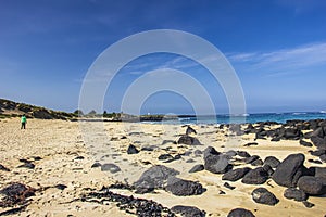 Black rocks scattered on the sandy beach of Griffiths Island of Port Fairy in Victoria, Australia.