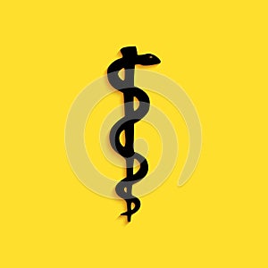 Black Rod of asclepius snake coiled up silhouette icon isolated on yellow background. Emblem for drugstore or medicine photo