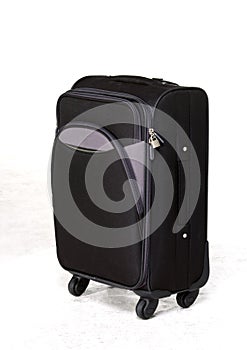black roller suitcase on white floor in front of white studio background