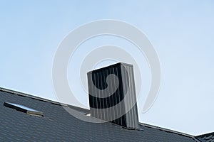 Black roofing of metal profile wavy shape. Roof with a skylight and a chimney