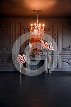 Black room interior with chandelier, mirror and fireplace decorated with flowers