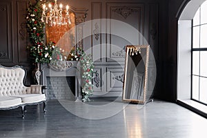 Black room interior with a vintage sofa, chandelier, mirror and fireplace decorated with flowers