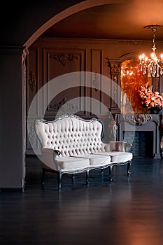 Black room interior with a vintage sofa, chandelier, mirror and fireplace decorated with flowers