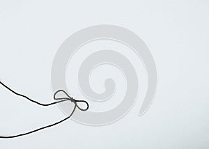 Black rope with ribbon tie on white background.