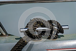 Black rope tied to the mooring cleat of a boat