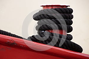 Black rope tied to a red metal mooring bollard