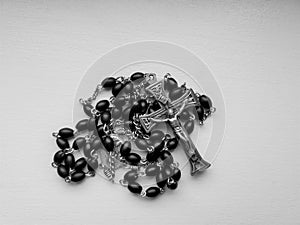 Black rosary beads with silver cross set against white background photo