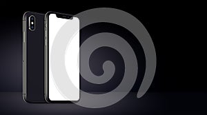 Black rotated smartphones similar to iPhone X mockup front and back sides on black background banner with copy space