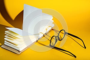 Black round glasses on a yellow background with hard shadow and the inscription look