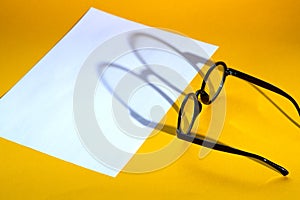 Black round glasses on a yellow background with hard shadow and the inscription look