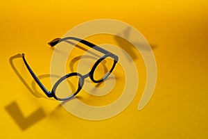 Black round glasses on a yellow background with hard shadow and the inscription look