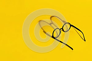 Black round glasses on a yellow background with hard shadow and the inscription look