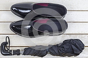 Black rubber boots with umbrella on white wooden table