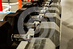 Black rubber dumbbells. Hexagonal heavy duty weight set used for serious hardcore gym workouts, cross fit training and