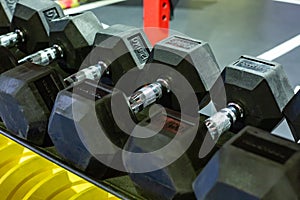 Black rubber dumbbells. Hexagonal heavy duty weight set used for serious hardcore gym workouts, cross fit training and