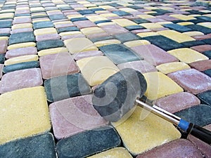Black rubber mallet lies on the surface of colored paving slabs, close-up