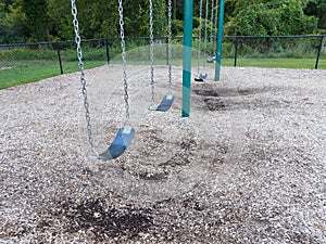 Black rubber swing seats with swingset and wood chips