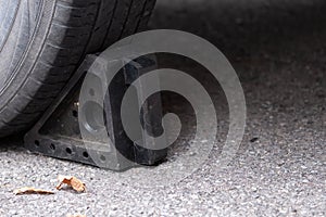 Black rubber wheel chock behind car tire