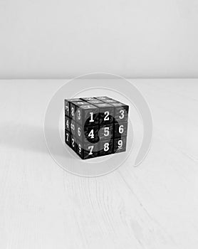 Black Rubik Cube with numbers on white wooden table shot of the part of side with numbers 1,2,4,5