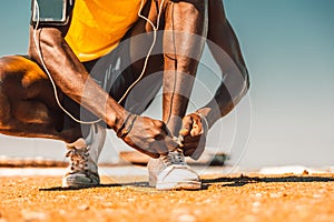 Black runner tie his shoes at the beach