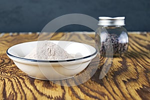 Black salt Kala namak in a glass salt shaker and on a plate on a wooden table