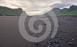 Černý písek pláž nejblíže v island zaostřené na kámen v popředí a hora rozsah v rozmazané 
