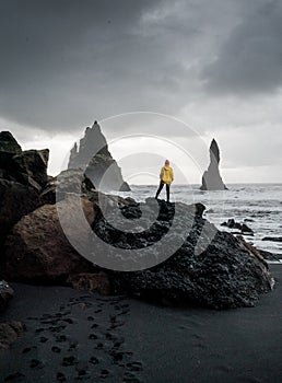 Black sand seach VIK Reynisfjara Iceland with a women yellow jacket