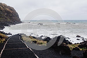 Black sand volcanic beach with white sea foam in Azores Islands.