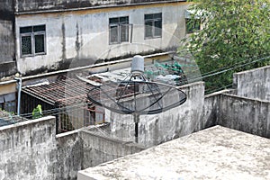 Black satellite dish and tv antenna at old village , parabolic digital receiver for communication data on roof