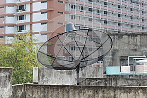 Black satellite dish and tv antenna at old village , parabolic digital receiver for communication data on roof