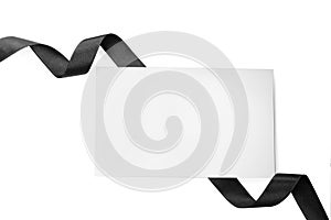 Black satin ribbon and blank card on white background, top view. Space for design