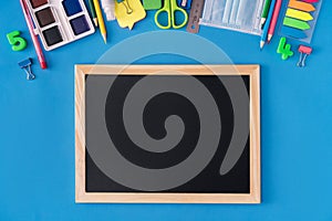 Black school board with school supplies on blue background. Back to school concept