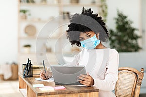 Black School Girl Learning Wearing Mask Using Digital Tablet Indoors