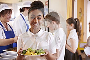 Black schoolgirl holds a plate of food in a school cafeteria