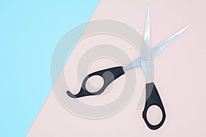 Black scissors on blue and pink paper.