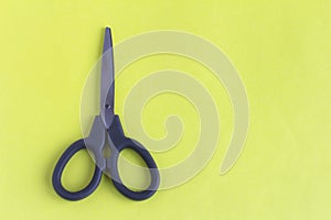 Black scissors on a yellow background.Small scissors for cutting