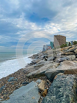 The Black Sea embankment. Rocky seashore in the city of Batumi. High-rise buildings by the sea.