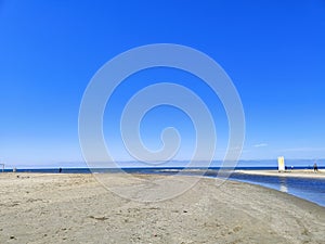 The Black Sea in spring with waves and sand on the beach with a bright blue sky.