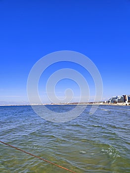 The Black Sea in spring with waves and sand on the beach with a bright blue sky.