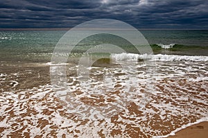 Black Sea. Water with waves. Dark cloudy weather. Deep bright blue water. Before storm. Sand coast