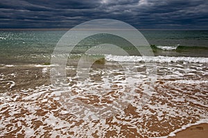 Black Sea. Water with waves. Dark cloudy weather. Deep bright blue water. Before storm. Sand coast