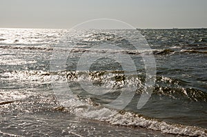 Black Sea. Water with waves. Mainly cloudy weather and sun rays. Blue and grey clouds. Before rain. Sand coast