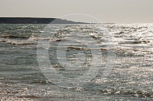 Black Sea. Water with waves. Mainly cloudy weather and sun rays. Blue and grey clouds. Before rain. Sand coast