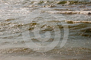 Black Sea. Water with waves. Mainly cloudy weather and sun rays. Blue and grey clouds. Before rain. Sand coast