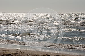 Black Sea. Water with waves. Mainly cloudy weather and sun rays. Blue and grey clouds. Before rain. Sand coast